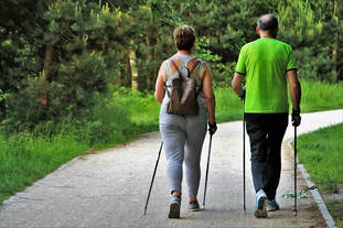 two people walking down nature trail using walking poles